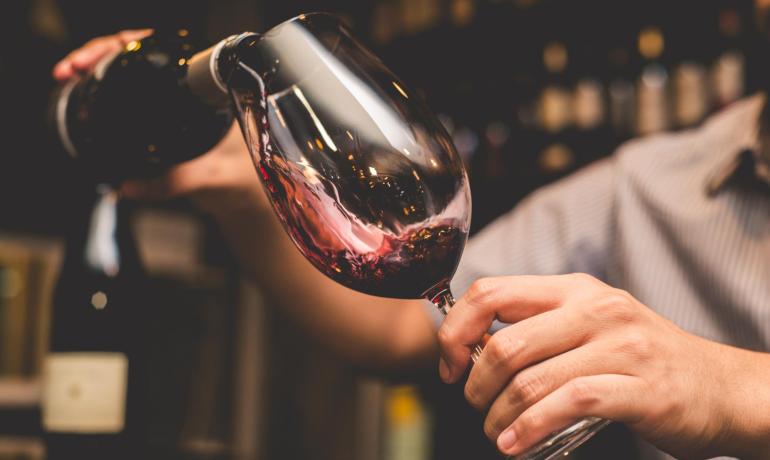 A glass of red wine is poured gracefully in a sophisticated setting.