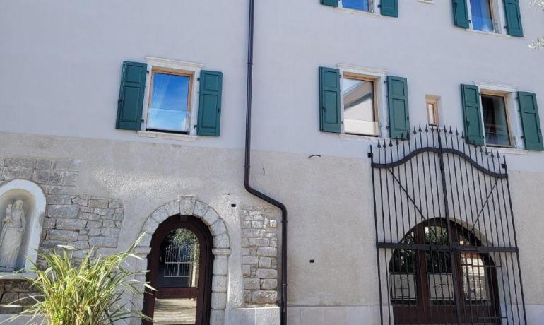 Edificio storico con persiane verdi, cielo azzurro e atmosfera serena.