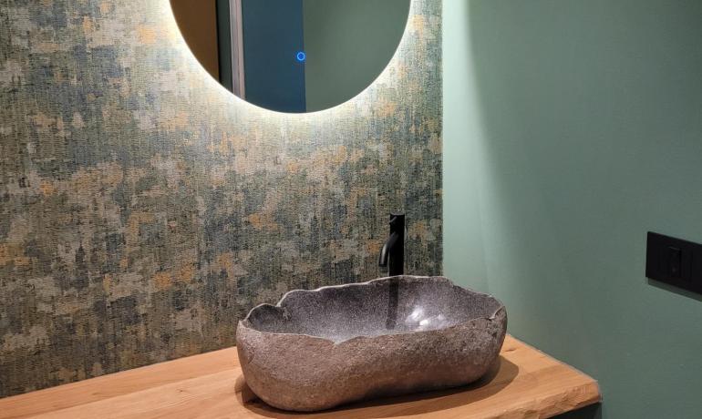 Elegantes Badezimmer mit leuchtendem Spiegel und Steinschale auf Holzregal.