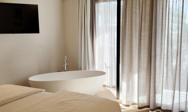 Camera luminosa con vasca elegante e tende leggere, atmosfera accogliente e rilassante.