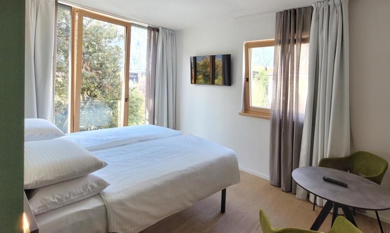 Helles Zimmer, gemütliches Bett, grüne Aussicht, ruhige und entspannende Atmosphäre.