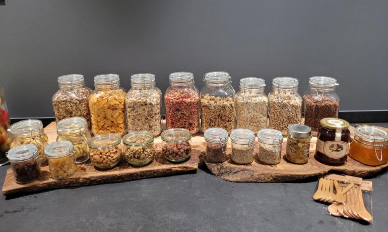 Jars of cereals and nuts on rustic board, warmth and abundance.