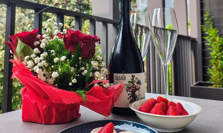 Romantic moment: flowers, wine, sweets, and strawberries on a scenic balcony.