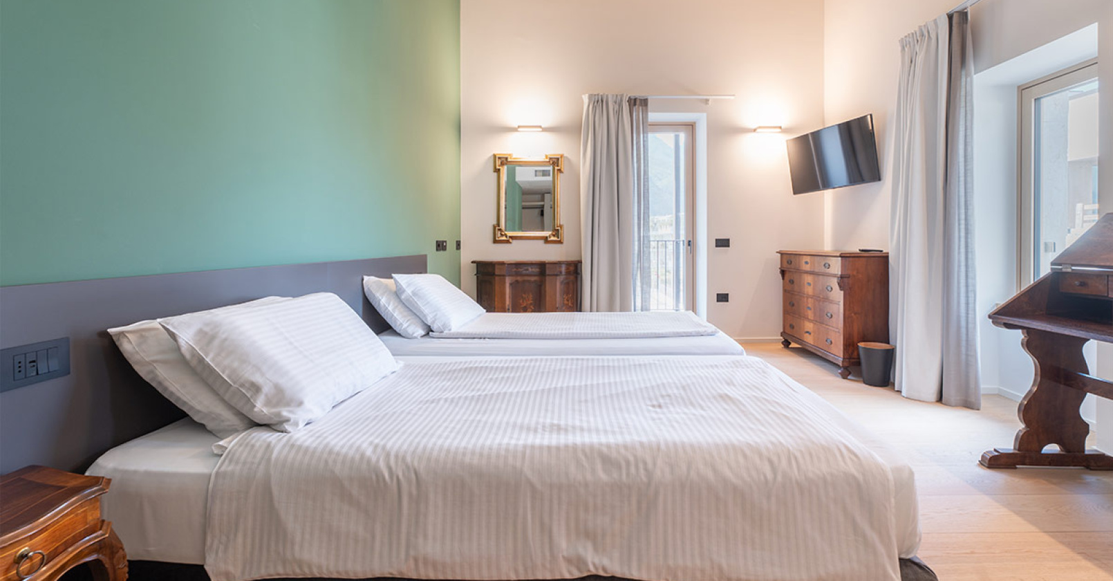 Camera moderna con letto, specchio e balcone luminoso.