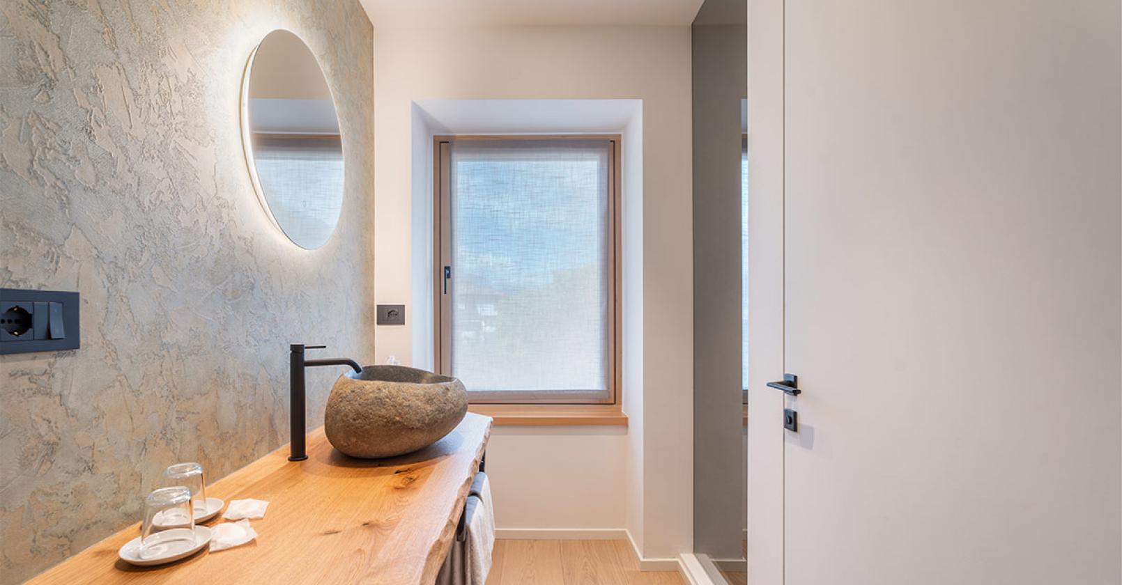 Bagno elegante con lavabo in pietra e specchio luminoso.