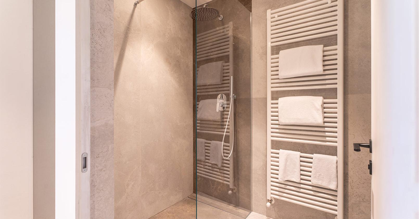 Elegante doccia moderna, calda atmosfera con asciugamani bianchi su porta asciugamani.