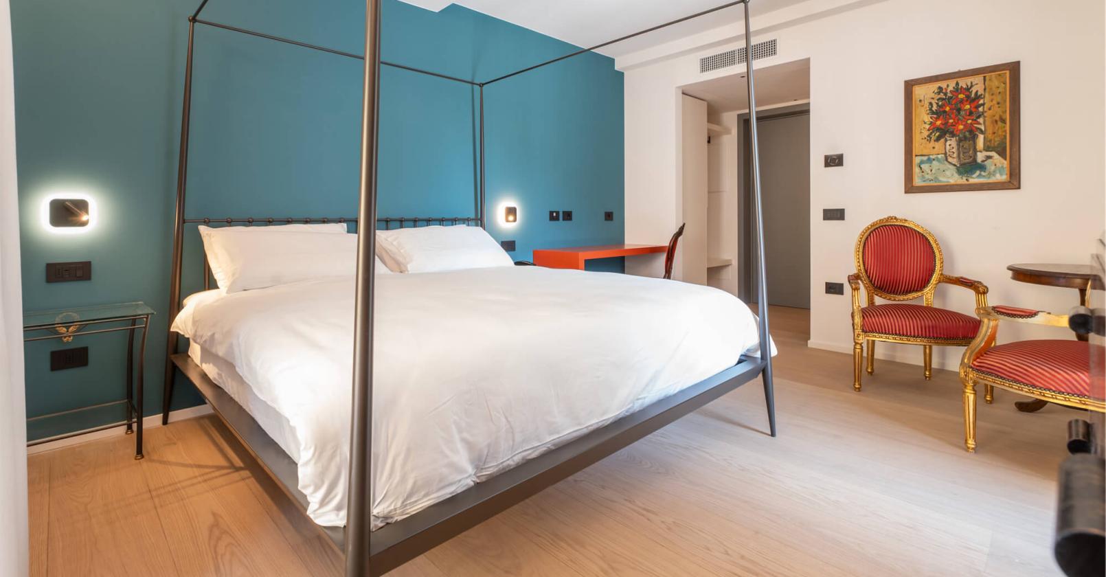 Elegantes Zimmer mit Himmelbett und klassischen Stühlen, gemütliche Atmosphäre.