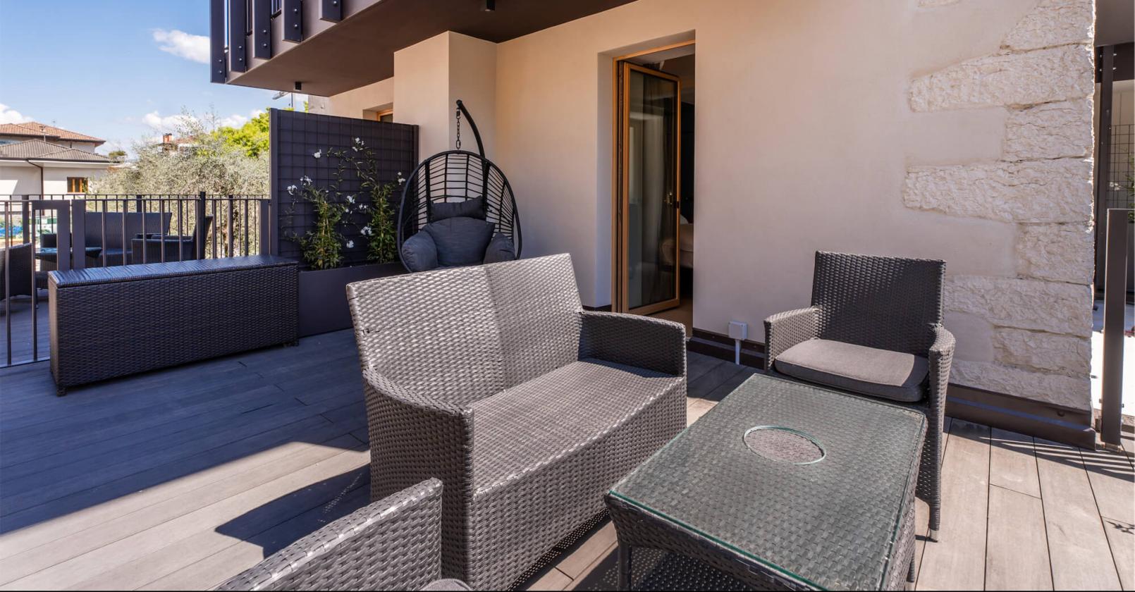 Moderne Terrasse mit Rattanmöbeln, blauer Himmel, entspannte Atmosphäre.