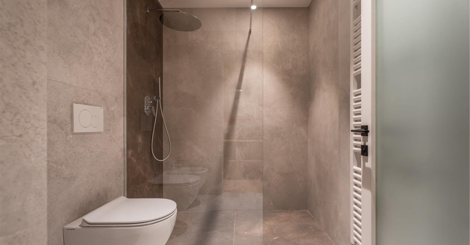 Modernes, minimalistisches Bad mit eleganter Dusche und Steinwänden.