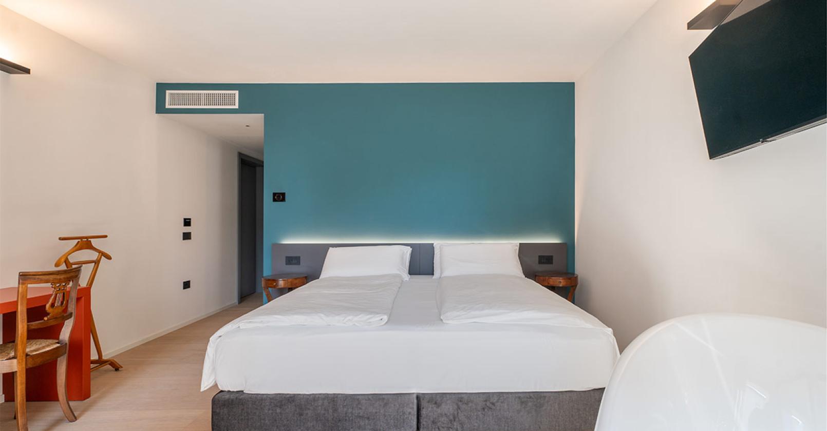 Camera moderna e luminosa con letto matrimoniale e parete blu.
