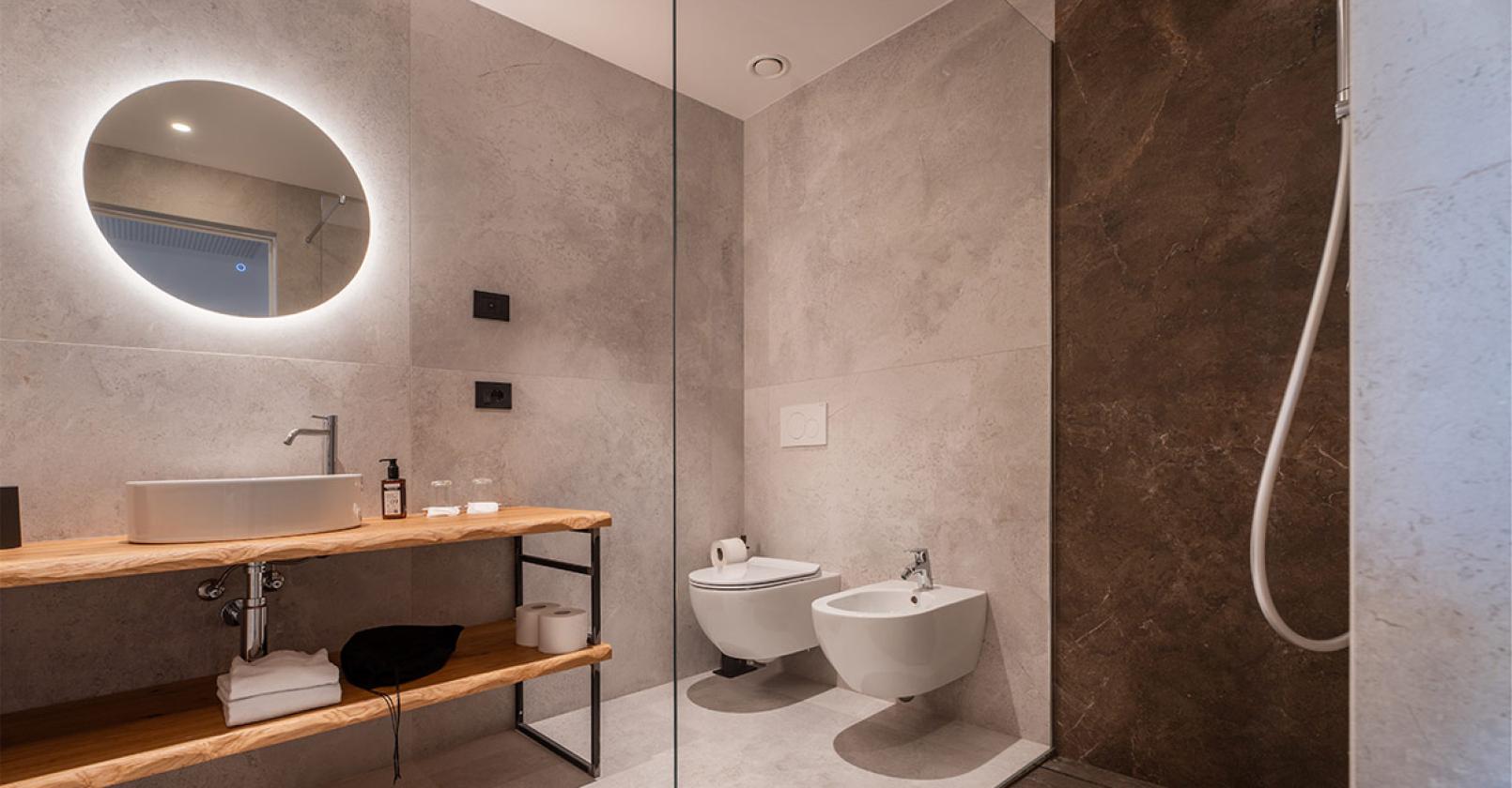 Elegante bagno moderno con finiture in pietra e luce soffusa.