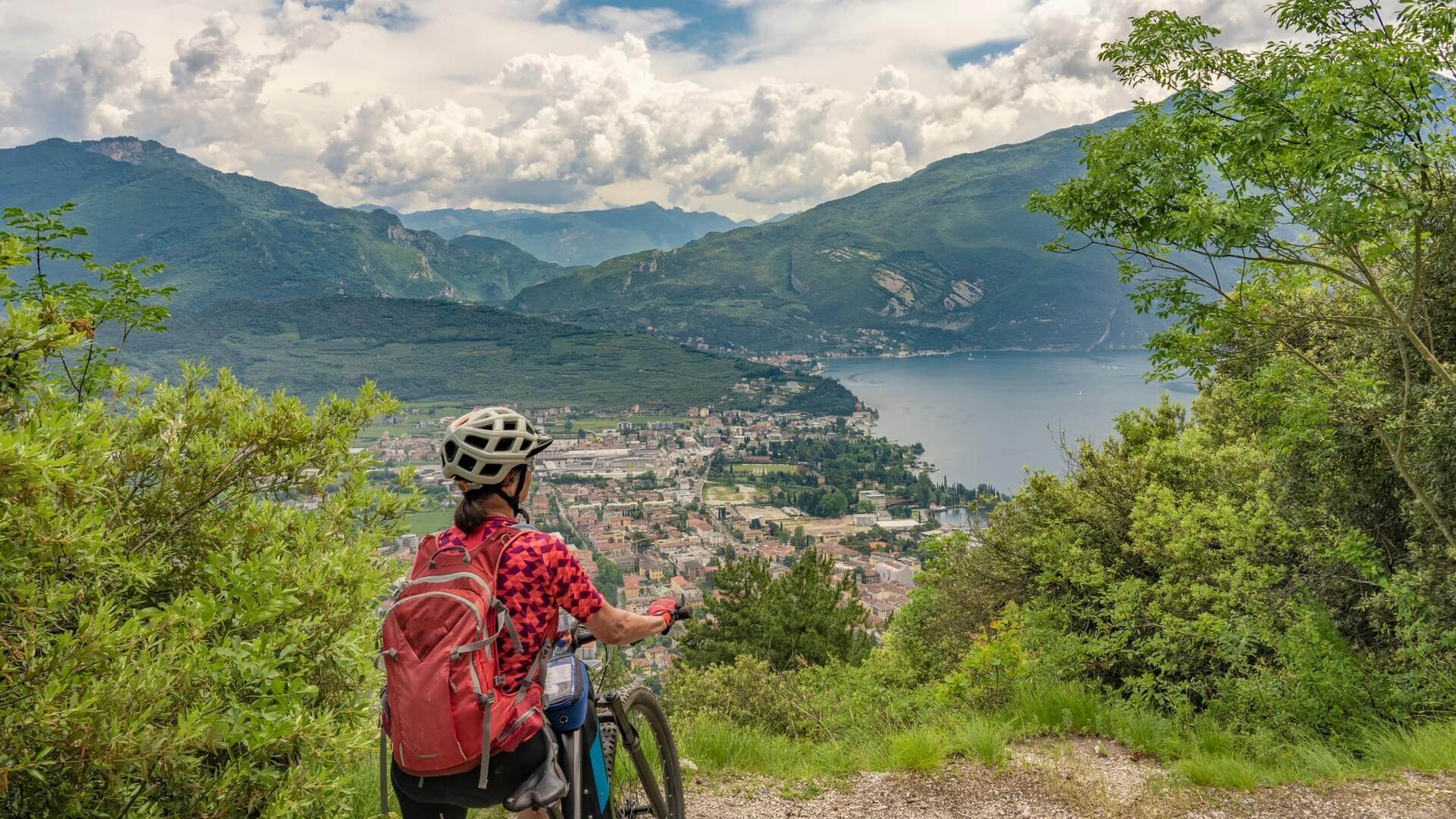 Ciclista ammira il panorama mozzafiato tra montagne e lago.